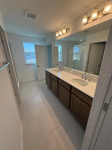a spacious bathroom with a double vanity sink a mirror and a shower