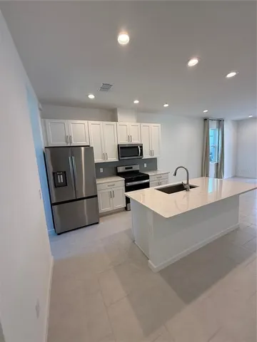 a kitchen with stainless steel appliances granite countertop a refrigerator a oven a sink a stove and white cabinets