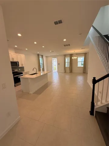 a view of an empty room with kitchen and a window