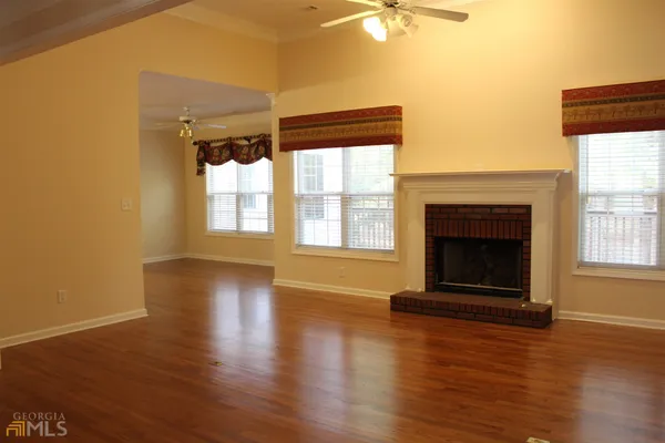 an empty room with wooden floor fireplace and windows