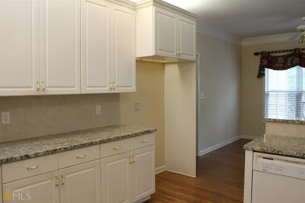 a kitchen with granite countertop white cabinets and a sink