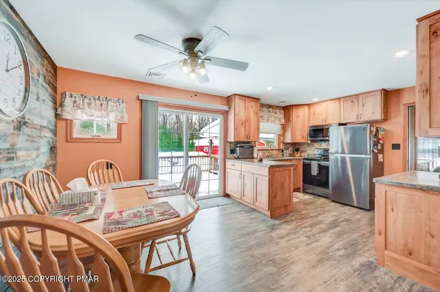 a kitchen with stainless steel appliances kitchen island granite countertop a stove a sink dishwasher a dining table and chairs with wooden floor