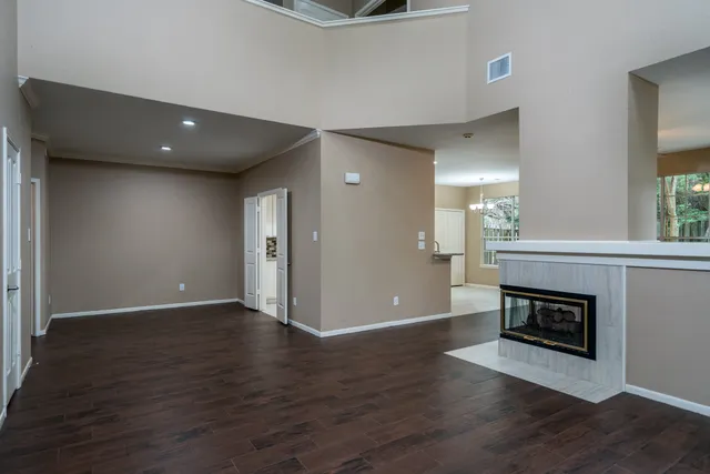 a view of an empty room with wooden floor and a fireplace