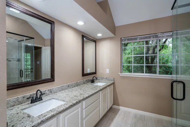 a bathroom with a granite countertop sink a mirror and a bathtub