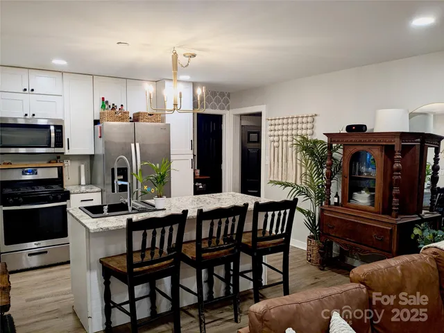 a kitchen with stainless steel appliances kitchen island granite countertop a table chairs and a refrigerator