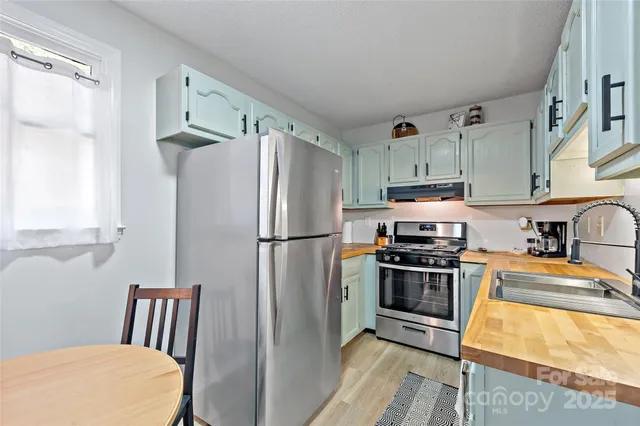 a kitchen with stainless steel appliances a refrigerator a stove a sink and white cabinets
