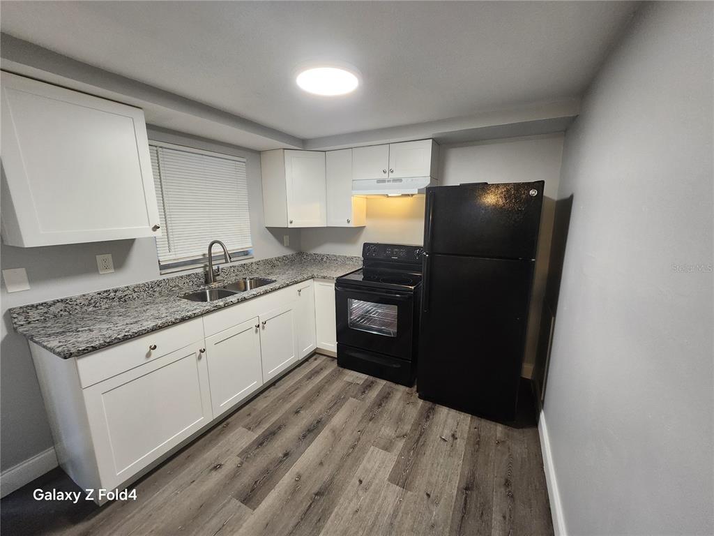 8012 Emi Ann Lane Riverview, FL 33578 - Photo 3 of 16 a kitchen with granite countertop a refrigerator a sink and white cabinets