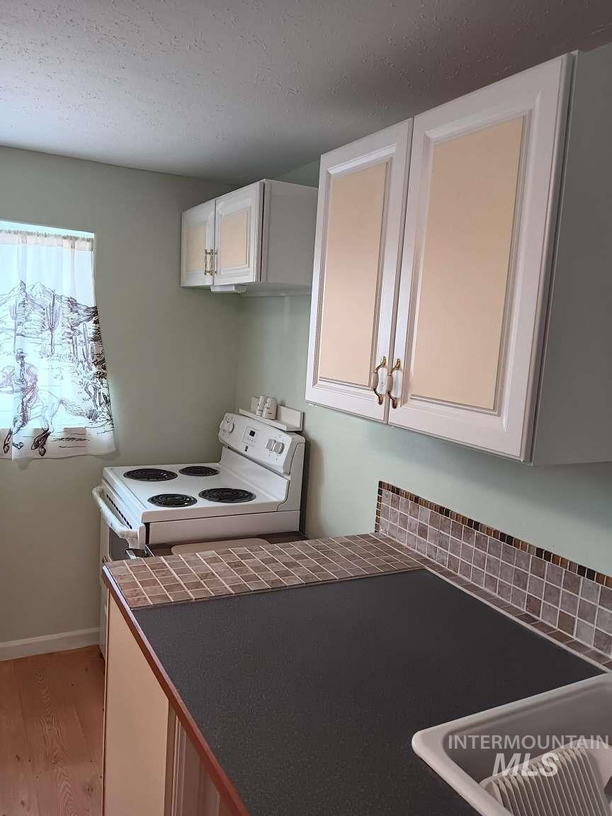 269 South State Street Hagerman, ID 83332 - Photo 14 of 29 Kitchen with white cabinetry, electric stove, light wood finished floors, and a textured ceiling