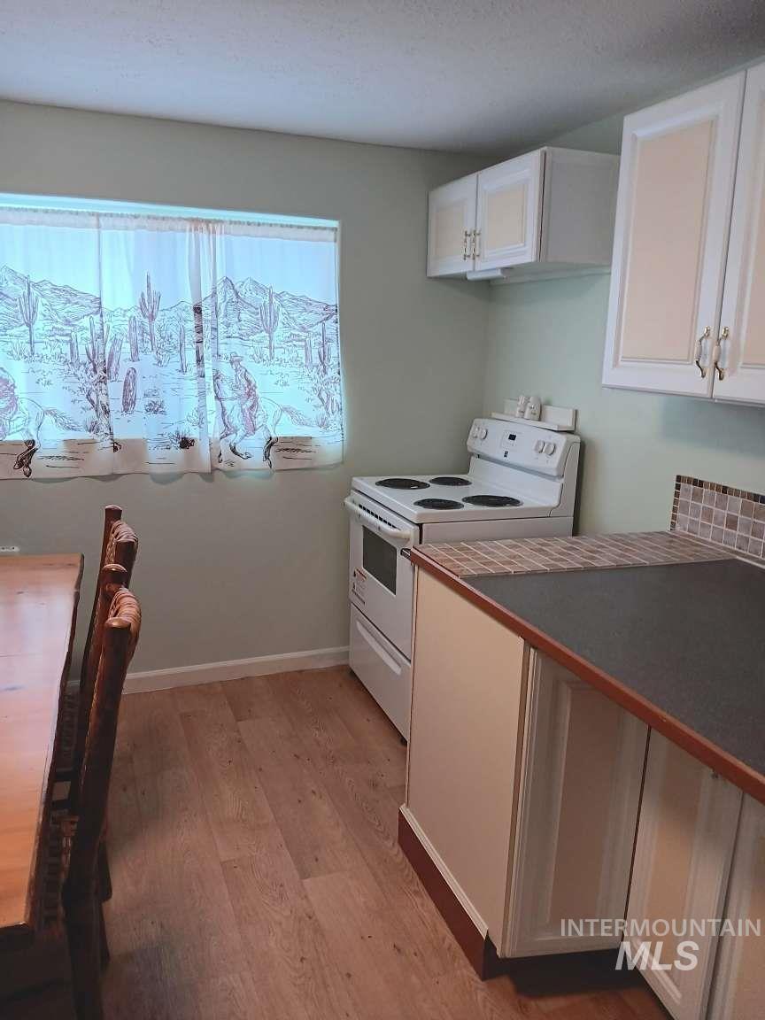 269 South State Street Hagerman, ID 83332 - Photo 15 of 29 Kitchen with white cabinets, white electric range oven, light wood finished floors, dark countertops, and a textured ceiling
