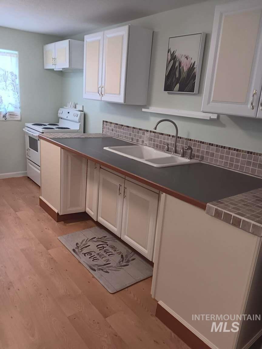 269 South State Street Hagerman, ID 83332 - Photo 16 of 29 Kitchen with white cabinets, light wood-style floors, and electric stove