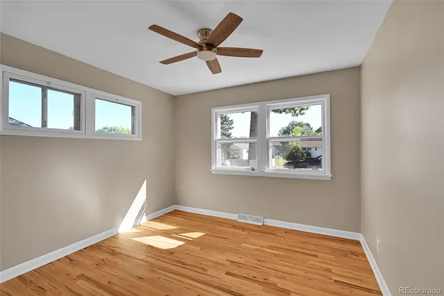 a view of empty room with wooden floor and fan
