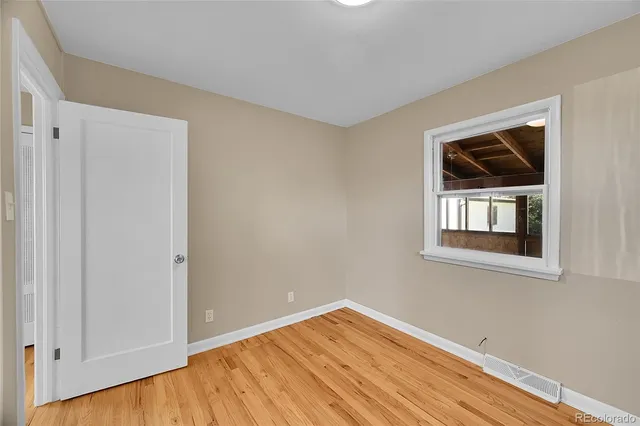 a view of an empty room with wooden floor and a window