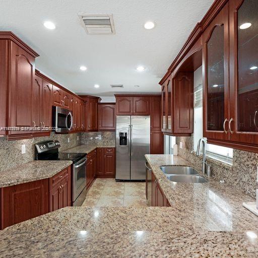 230 Southwest 30th Avenue, Unit 230 Miami, FL 33135 - Photo 3 of 22 a kitchen with stainless steel appliances granite countertop a stove a sink a refrigerator and a wooden cabinets