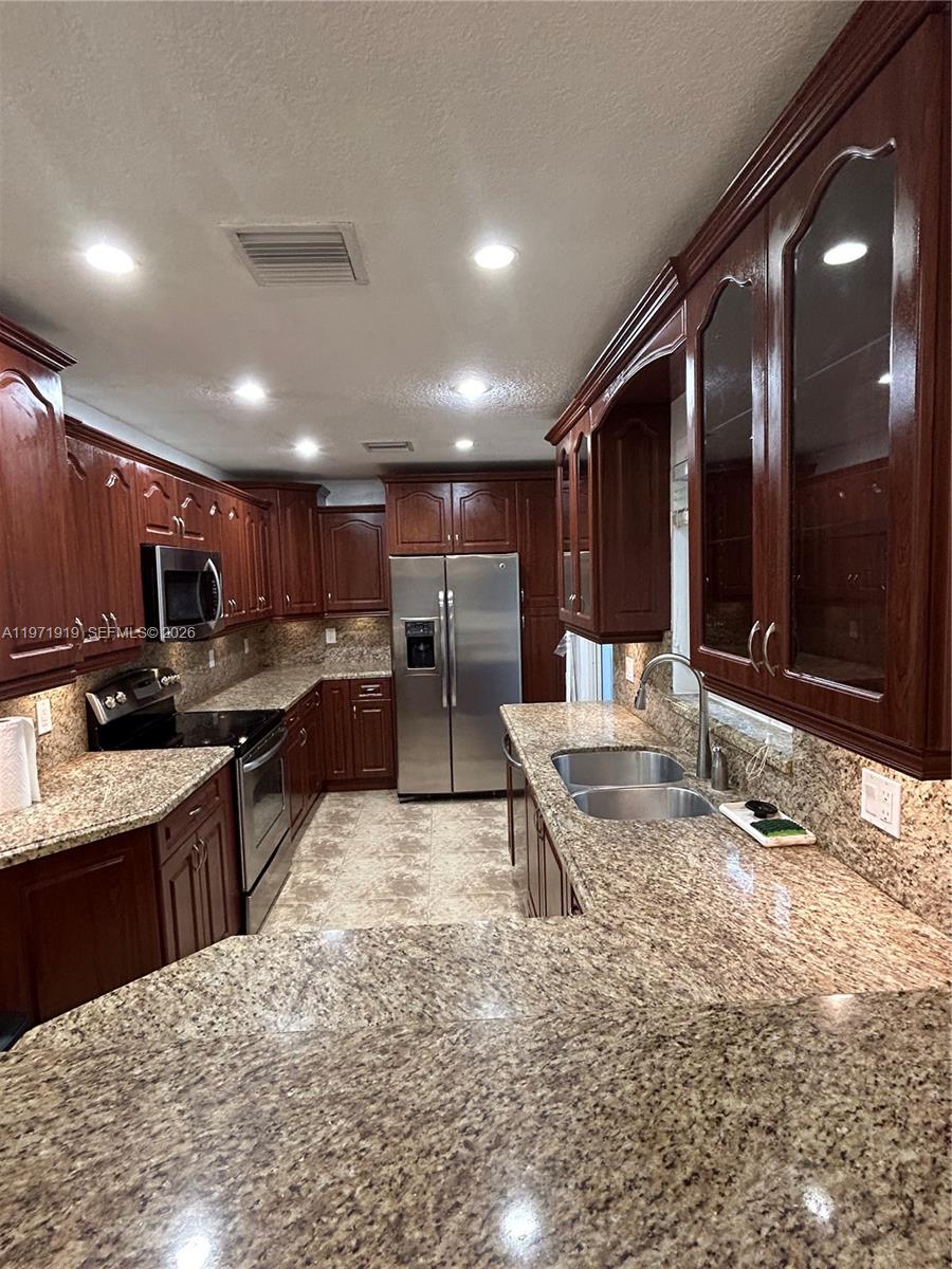 230 Southwest 30th Avenue, Unit 230 Miami, FL 33135 - Photo 4 of 22 a kitchen with stainless steel appliances kitchen island granite countertop a sink and cabinets
