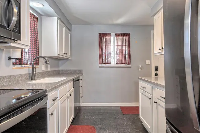 a kitchen with granite countertop a sink stove and cabinets