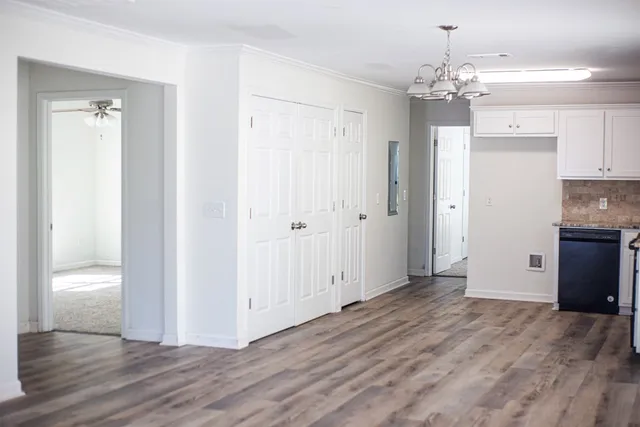 a view of a hallway with wooden floor and chandelier