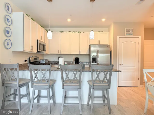 a kitchen with stainless steel appliances granite countertop a table chairs sink and cabinets