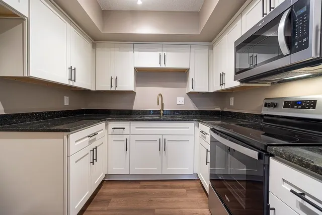 a white kitchen with granite countertop stainless steel appliances