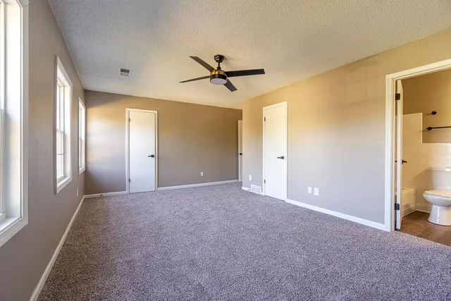 a view of a livingroom with a chandelier fan and windows