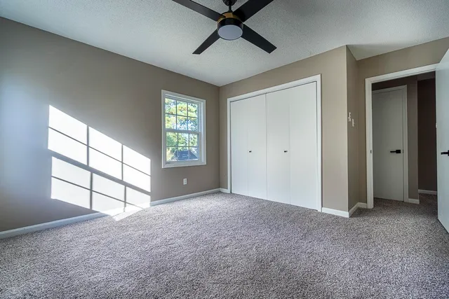 an empty room with windows and ceiling fan