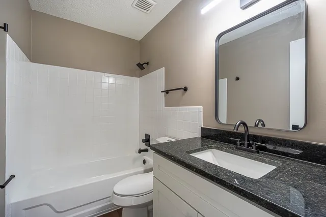 a bathroom with a granite countertop sink a mirror and a toilet