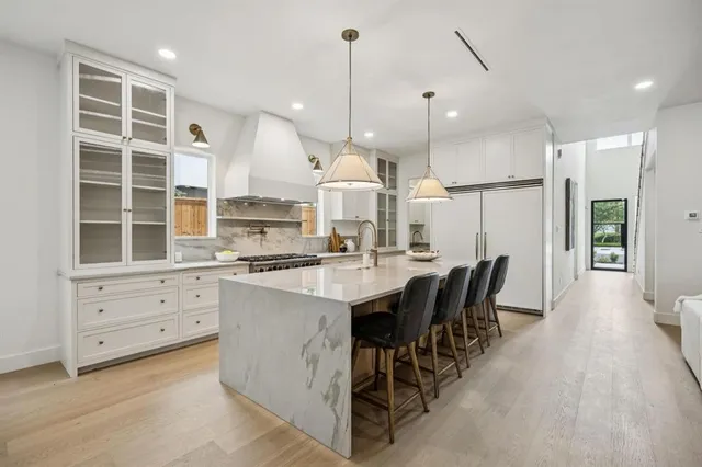 a kitchen with stainless steel appliances kitchen island granite countertop a stove a sink a oven a dining table and chairs with wooden floor