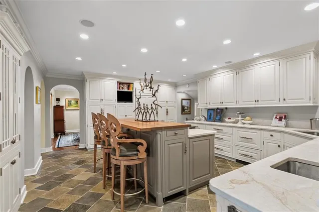 a kitchen with stainless steel appliances kitchen island granite countertop a table chairs sink and cabinets