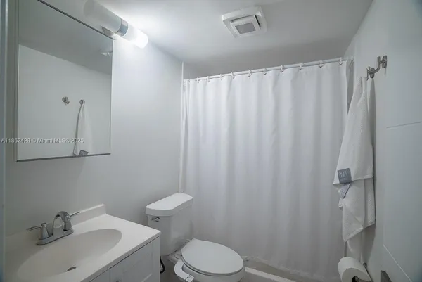 a bathroom with a sink a toilet and shower curtain