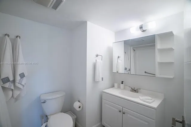 a bathroom with a toilet sink vanity and mirror
