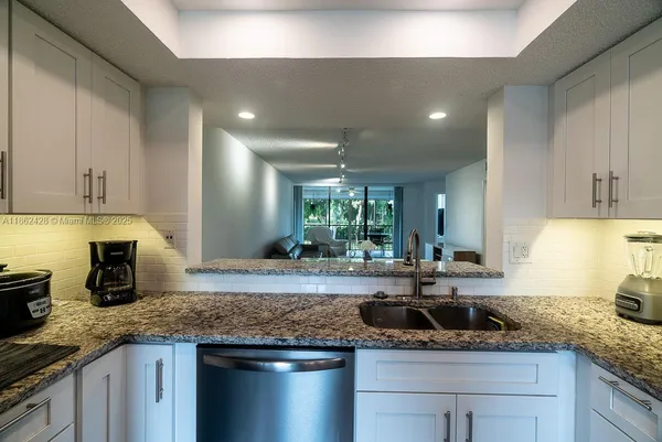 a kitchen with kitchen island granite countertop a sink and white cabinets
