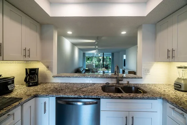 a kitchen with kitchen island granite countertop a sink and white cabinets