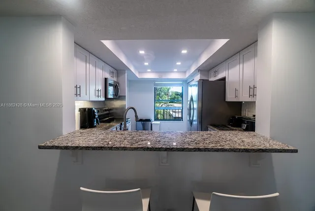 a kitchen with stainless steel appliances a table and chairs in it