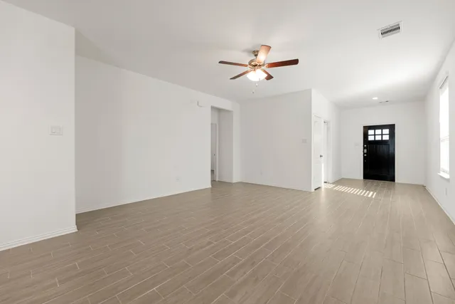 an empty room with wooden floor closet and fan chandelier fan