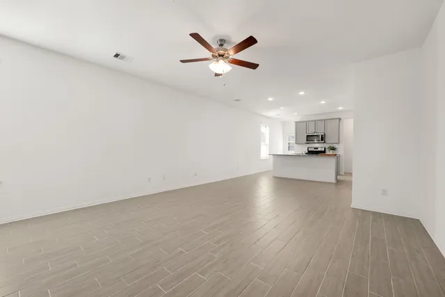a view of empty room with wooden floor and ceiling fan