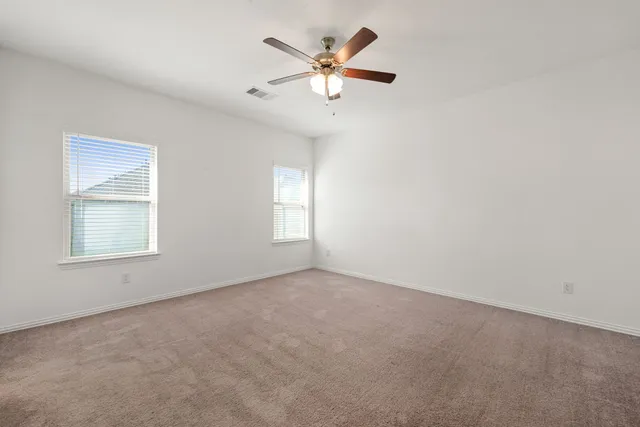 an empty room with a window and a ceiling fan