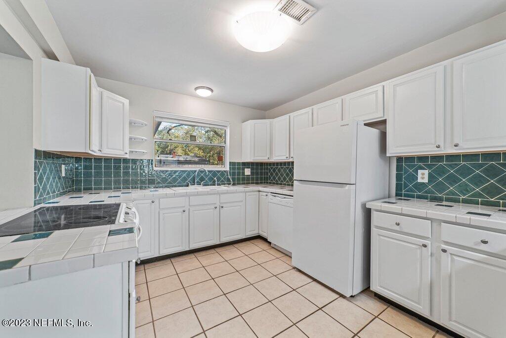 6147 Temple Road Jacksonville, FL 32217 - Photo 10 of 36 a kitchen with white cabinets and white appliances