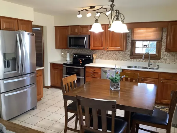 a kitchen with stainless steel appliances granite countertop a sink a stove a refrigerator a dining table and chairs