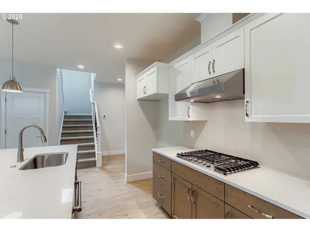 a kitchen with kitchen island stainless steel appliances a sink a stove and a refrigerator