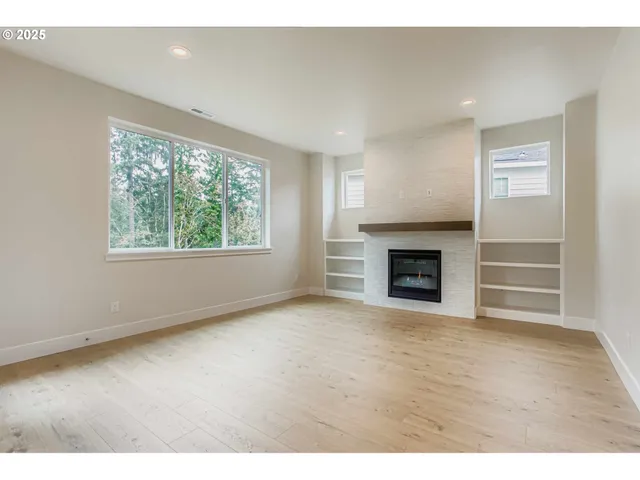 a view of an empty room with a window and fireplace
