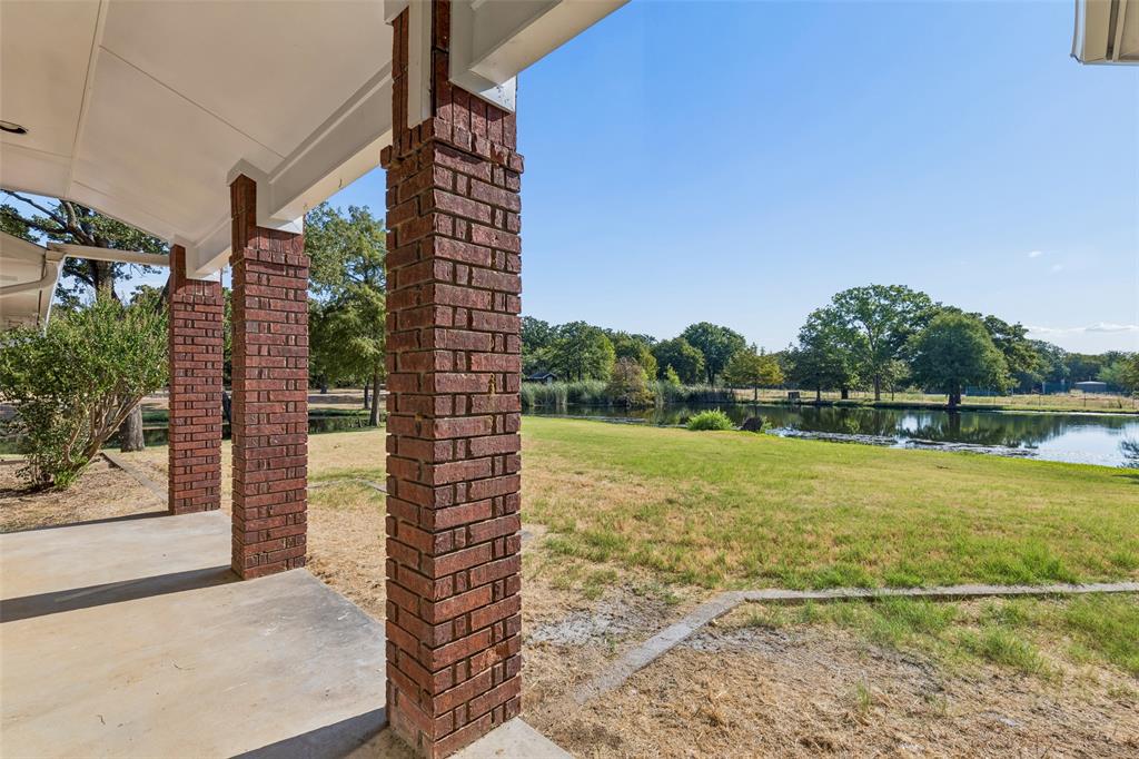 1155 Point Vista Road Hickory Creek, TX 75065 - Photo 26 of 40 Covered patio with brick columns, concrete flooring, expansive green space, and a prominent water feature
