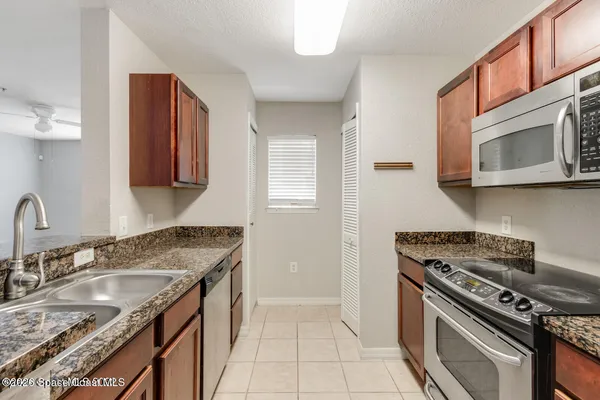 a kitchen with granite countertop a sink stove and microwave