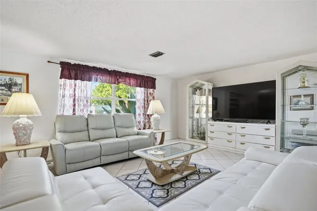 a living room with furniture a flat screen tv and a large window