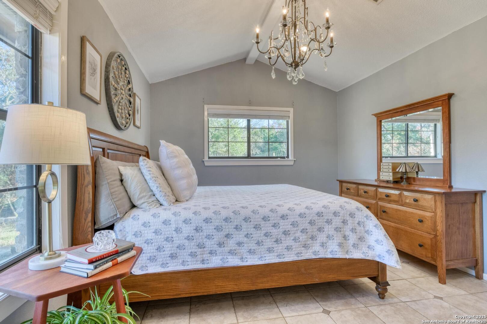 105 Shane Lane Boerne, TX 78006 - Photo 25 of 64 a bedroom with a large bed and a chandelier