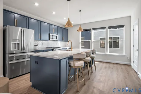 a kitchen with kitchen island a refrigerator a stove a dining table and chairs with wooden floor