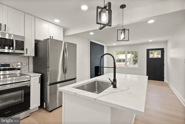 a large kitchen with stainless steel appliances kitchen island granite countertop a refrigerator a stove a sink and a microwave