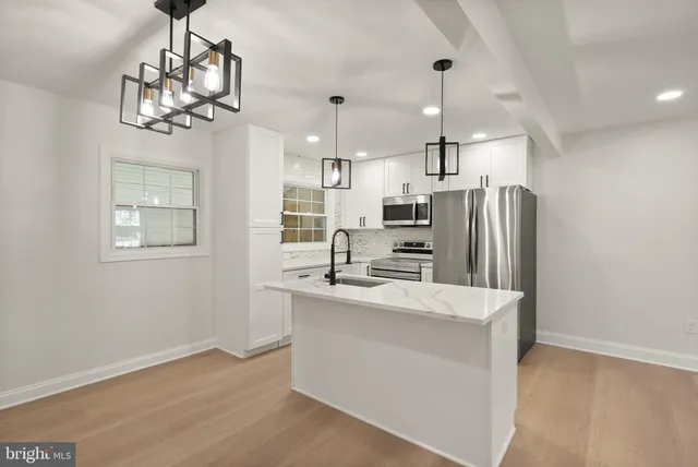 a kitchen with white cabinets and sink
