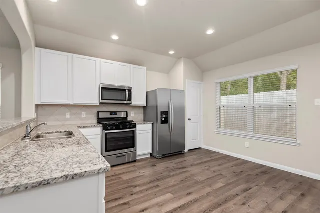 a kitchen with granite countertop a stove a sink and a refrigerator