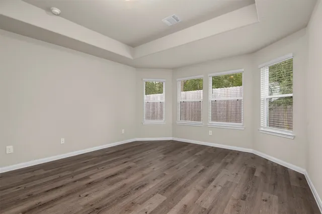 a view of an empty room with wooden floor and a window