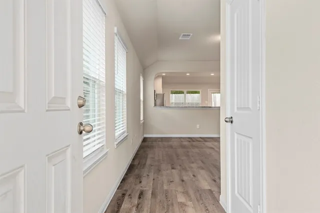 a view of a hallway with wooden floor and windows