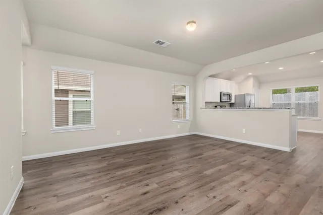 an empty room with wooden floor and windows